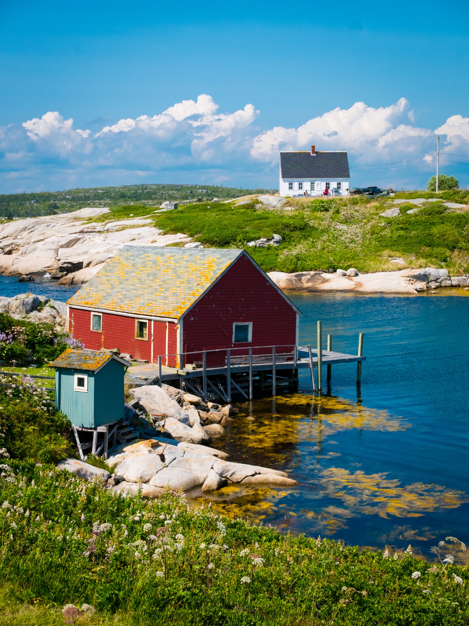 Red and white coastal houses beside clear blue water and rocky terrain