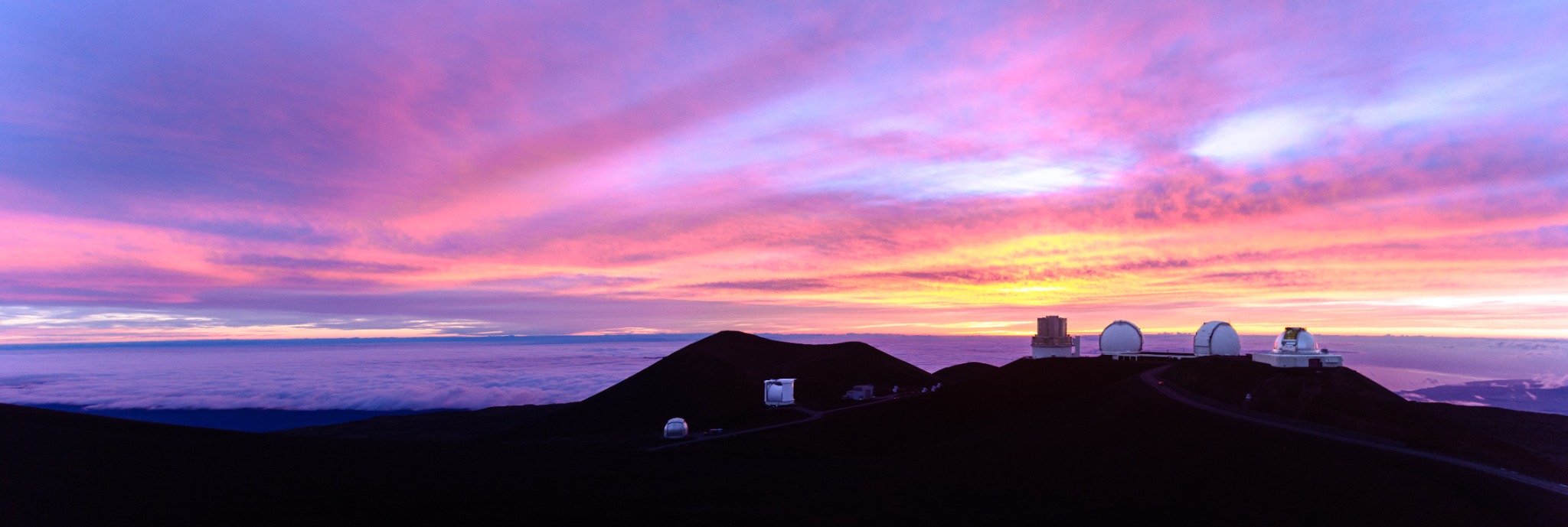 Panoramic sunset above a mountaintop observatory and a sea of clouds